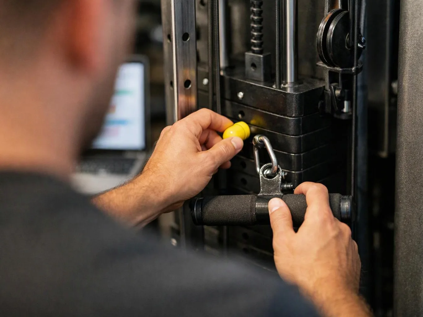 A person adjusts a weight machine with both hands in a gym setting